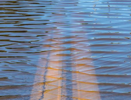 double yellow center lines of a road disappearing into deep water