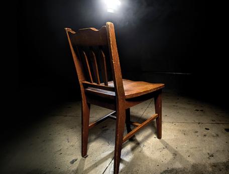 empty wooden chair with spotlight trained on it