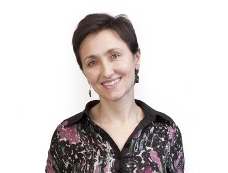 woman with short dark hair and a flower dress against a white backgroun