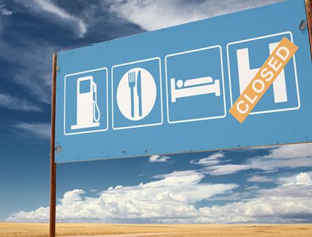 highway sign with "closed" sticker over hospital icon