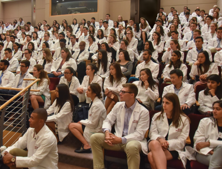 A group of students in white coats at a lecture
