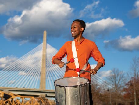 portrait of Yoseph Boku playing a drum outdoors