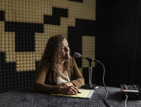 Anne Hallward sits in a radio recording studio in front of a mircophone