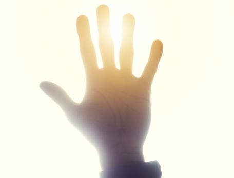 Looking up towards a hand that is blocking the sun