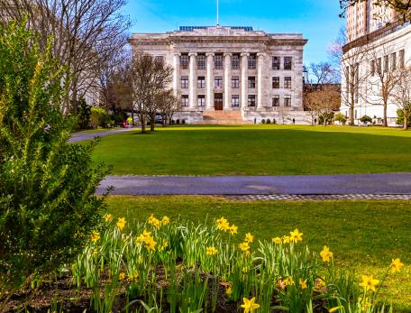 A pathway on the HMS Quad with Gordon Hall in the background and daffodils in the foreground.