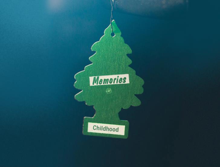 A green, tree-shaped car air freshener that says "childhood memories"
