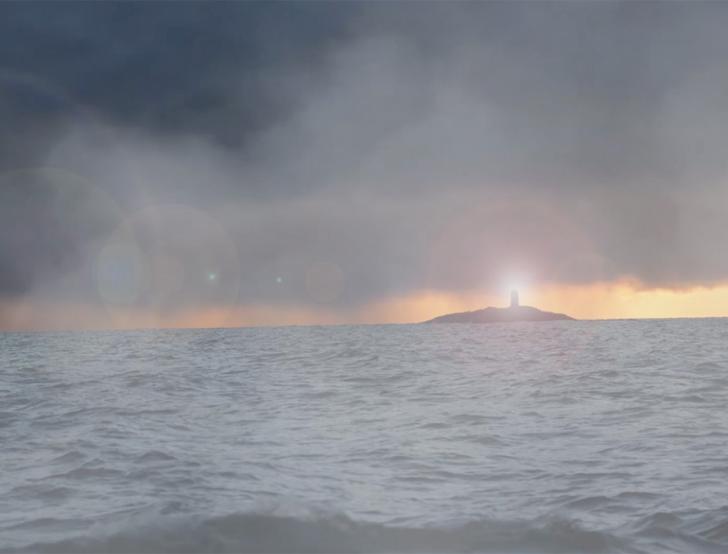 A lighthouse shines through the fog