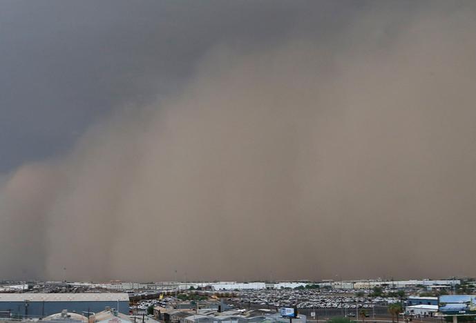 Dust storm rolling in over landscape dotted with small buildings