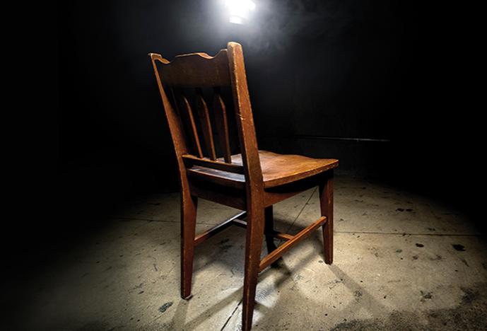 empty wooden chair with spotlight trained on it