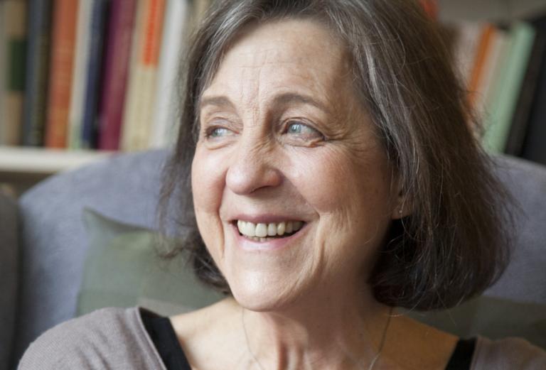 close up of a woman sitting in front of a bookshelf