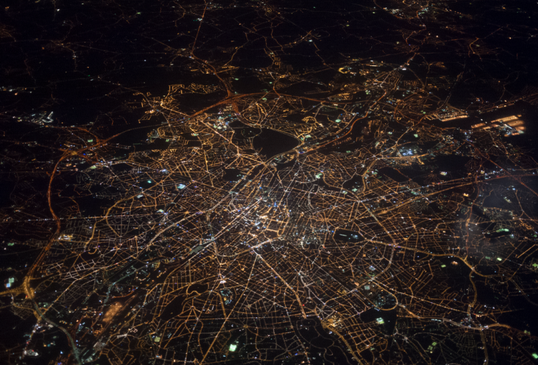 night image of the lighted grid of a city as seen from a high altitude