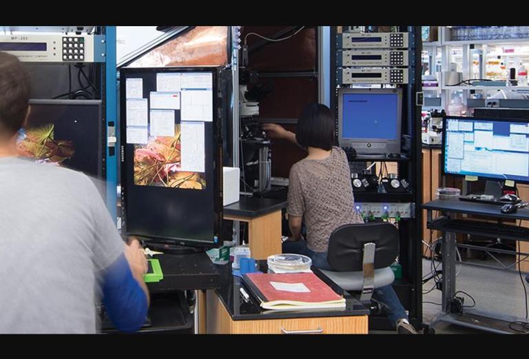 scientists work in a lab space filled with various computers and instruments