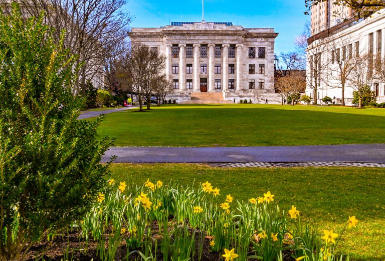 A pathway on the HMS Quad with Gordon Hall in the background and daffodils in the foreground.