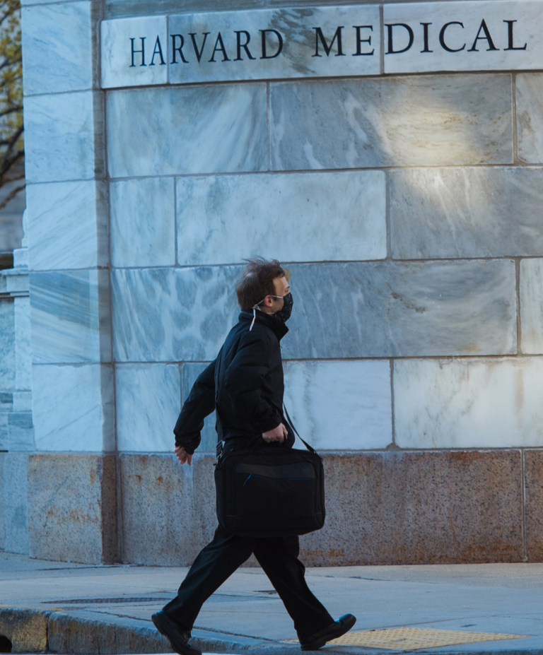 man carrying briefcase and wearing a face mask on HMS campus