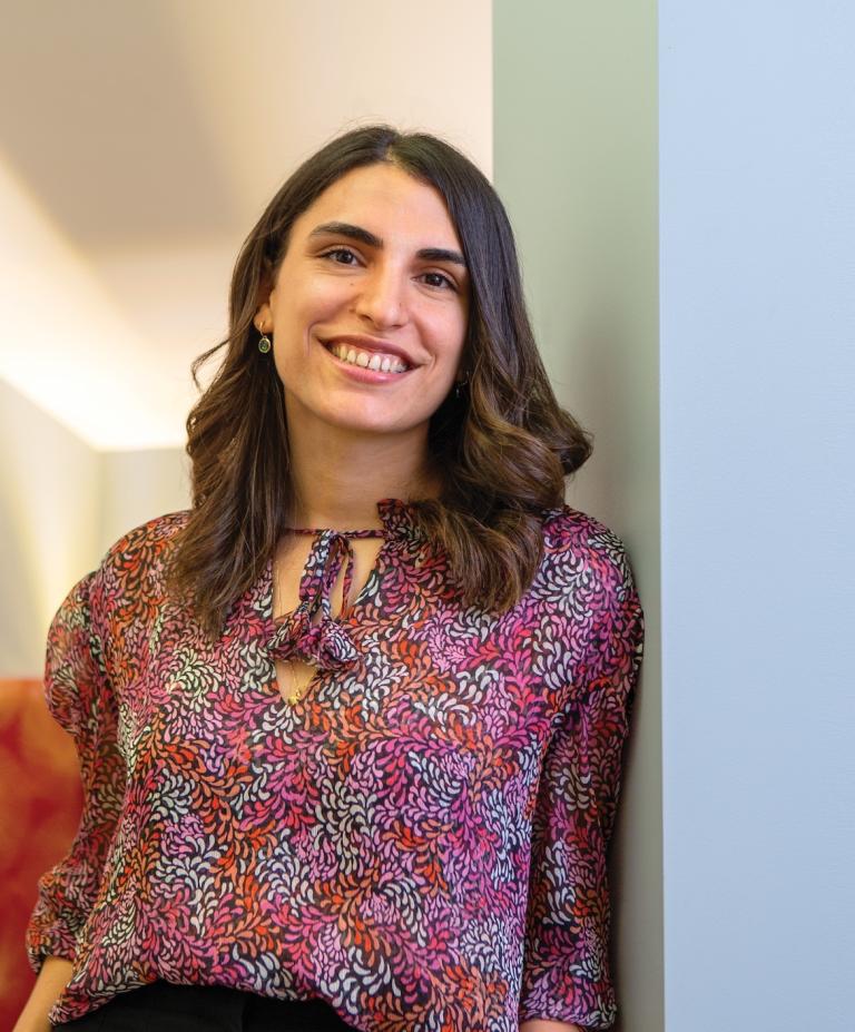 Aya Awwad leans against a white wall and smiles for the camera