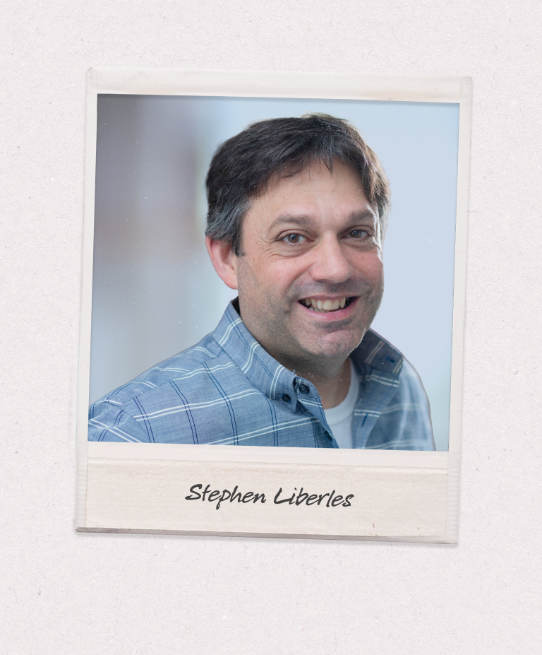 A polaroid-style image against a beige background shows a man with brown hair in a blue button down shirt smiling at the camera