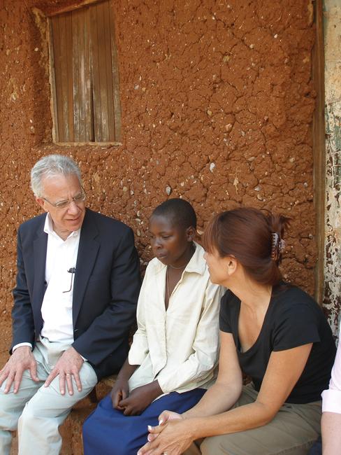 Lawrence Shulman (left) sits with a patient and colleague outside a clinic in Rwanda.