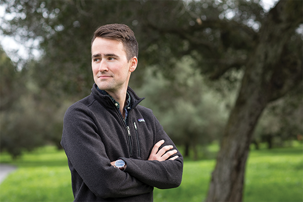 portrait of Ned Morris, arms crossed looking off camera, standing outdoors