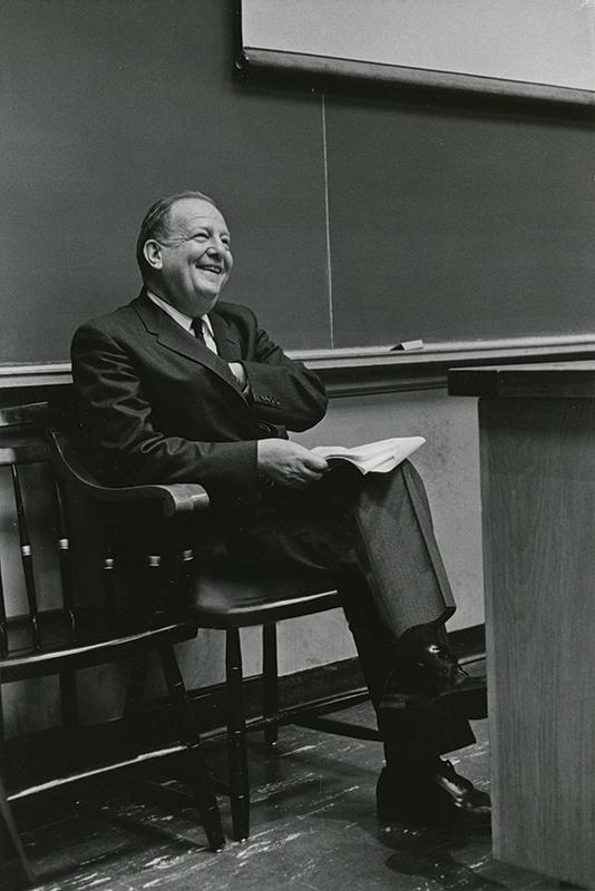 portrait of Daniel H. Funkenstein smiling and seated in the front of a classroom