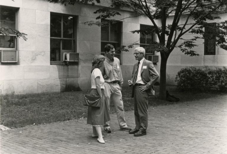 black and white photo of Gerald Foster standing outdoors and talking with two medical students