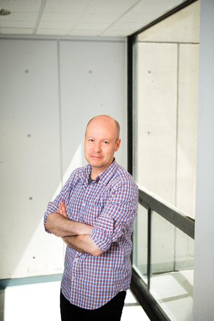 man in purple shirt next to a window