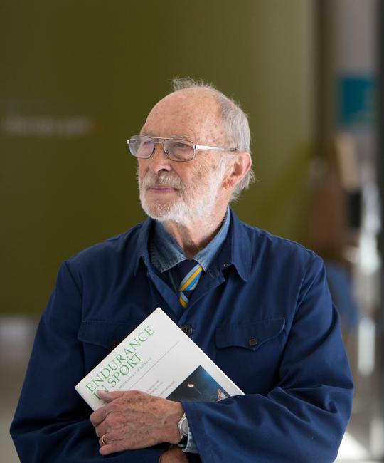 man holding white book in a blue coat and tie