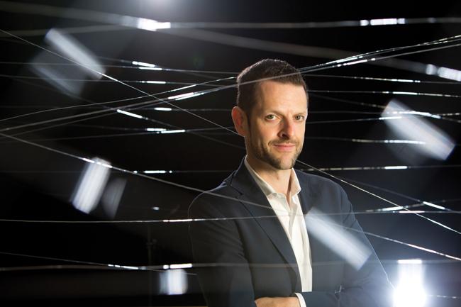 man in suit coat with black background and white lights around him