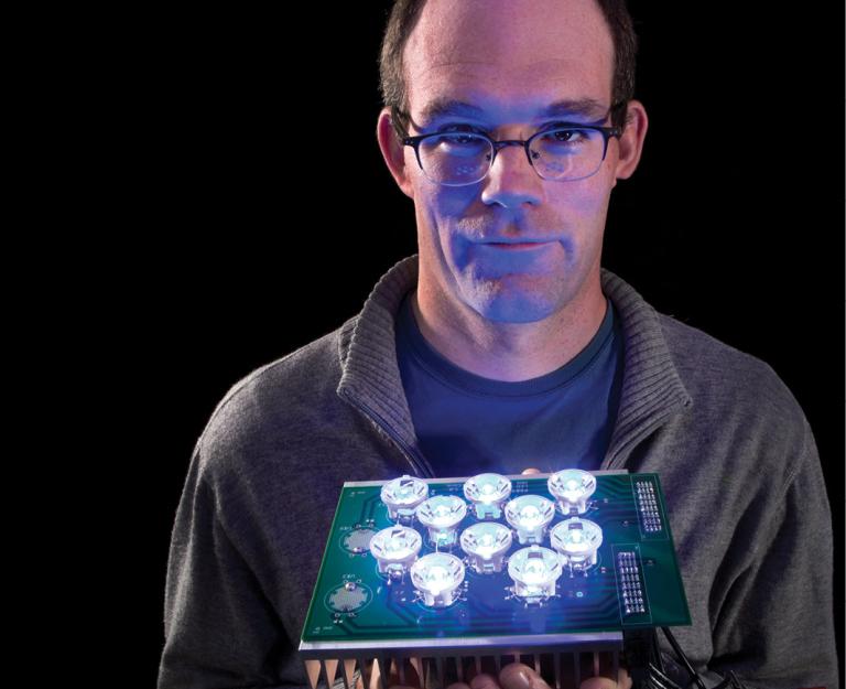 man in glasses holding a board with circle lights