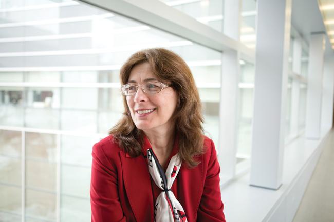 woman in red blazer and scarf in front of a lab window