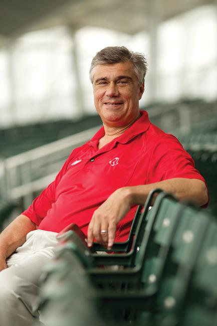 laurance ronan sitting in a green chair at a baseball stadium