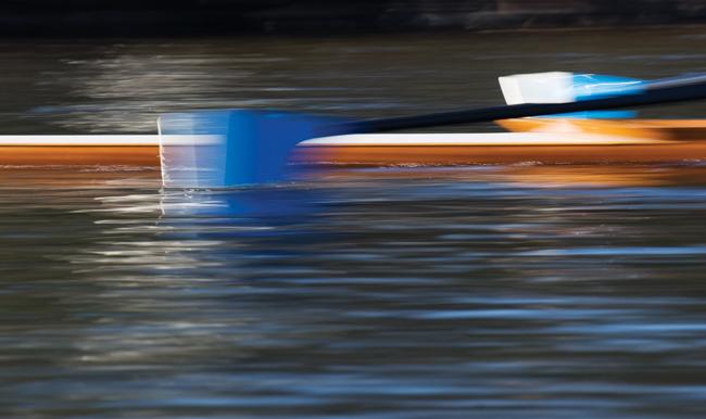 blurry photo of oars in the water by a rowing boat
