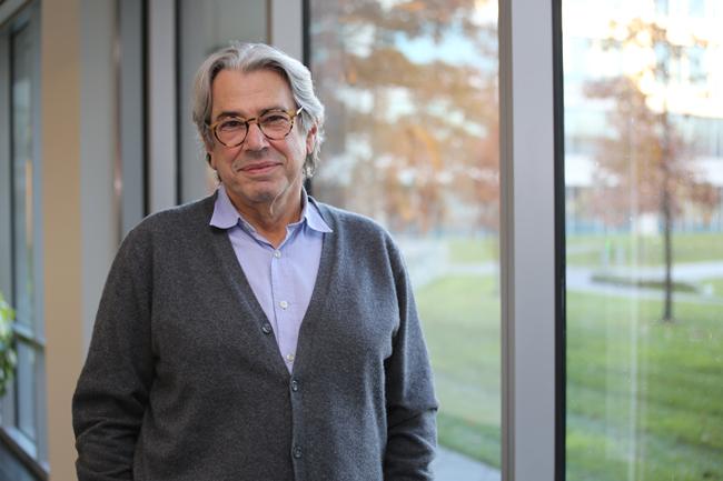 man with glasses in sweater by window