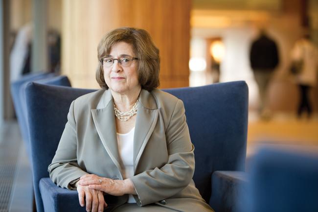 woman in tan suit sitting in blue chair