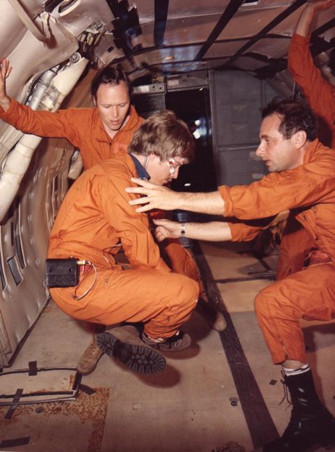 Photo of Charles Oman being examined by two colleagues inside aircraft displaying weightless environment