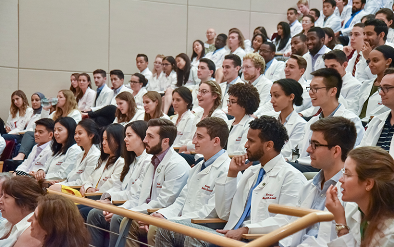 A group of students in white coats at a lecture