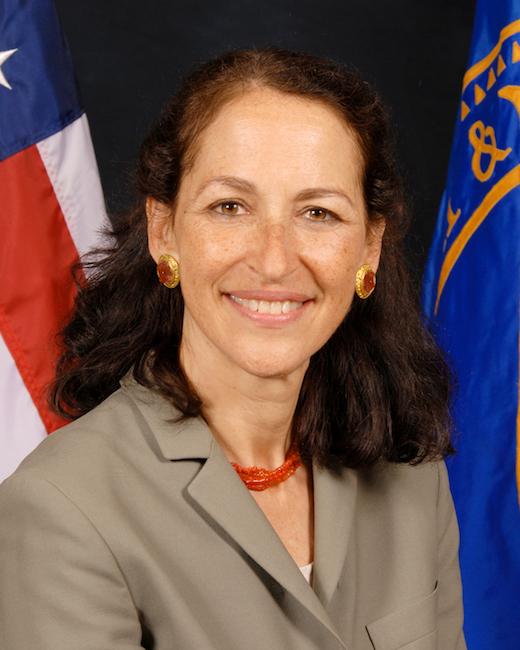 woman in tan suit in front of american flag