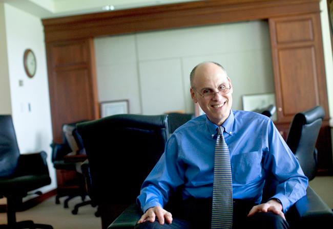 man in blue dress shirt and tie sitting in a char