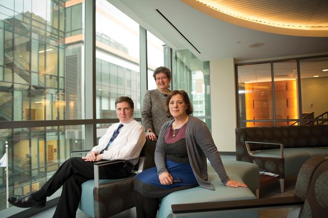 a man and two women on a couch near a glass wall