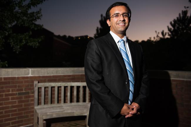 man in black suit on a brick patio with night sky behind him