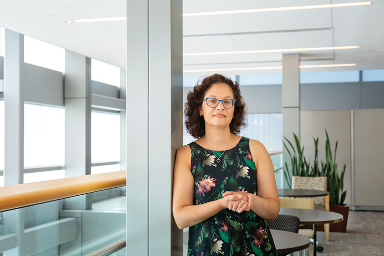 Usha Tedrow stands, leaning on a pole, in a brightly lit room