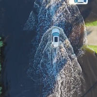 An overhead shot of a car driving through a flooded road