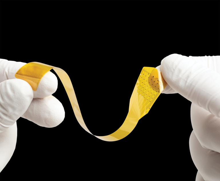 Two hands in latex gloves hold up a small yellow strip.