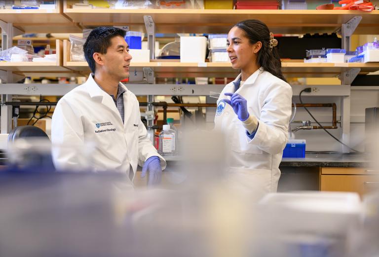 Two scientists wearing white coats in a science lab.