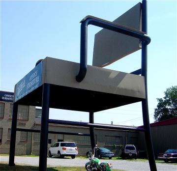 A giant chair outside of a beige brick building reads "Miller's Office Furniture"