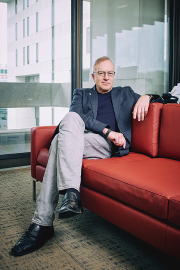 A man sits on a red couch looking at the camera