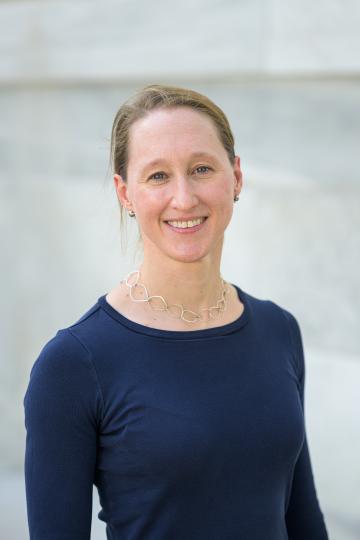 Sloan Devlin smiles at the camera against a grey background