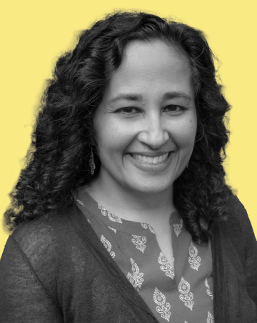 A headshot of a smiling woman with curly brown hair against a bright yellow background.